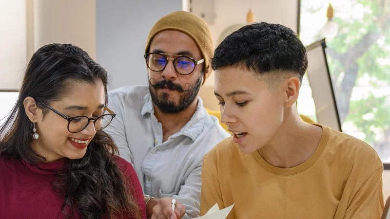 Three colleagues reviewing a document together at their laptops in a bright office