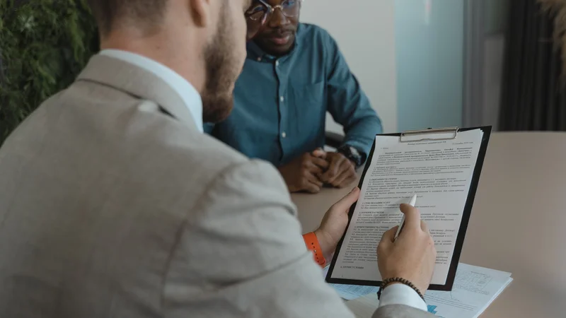 Two colleagues reviewing a formal document together on a clipboard